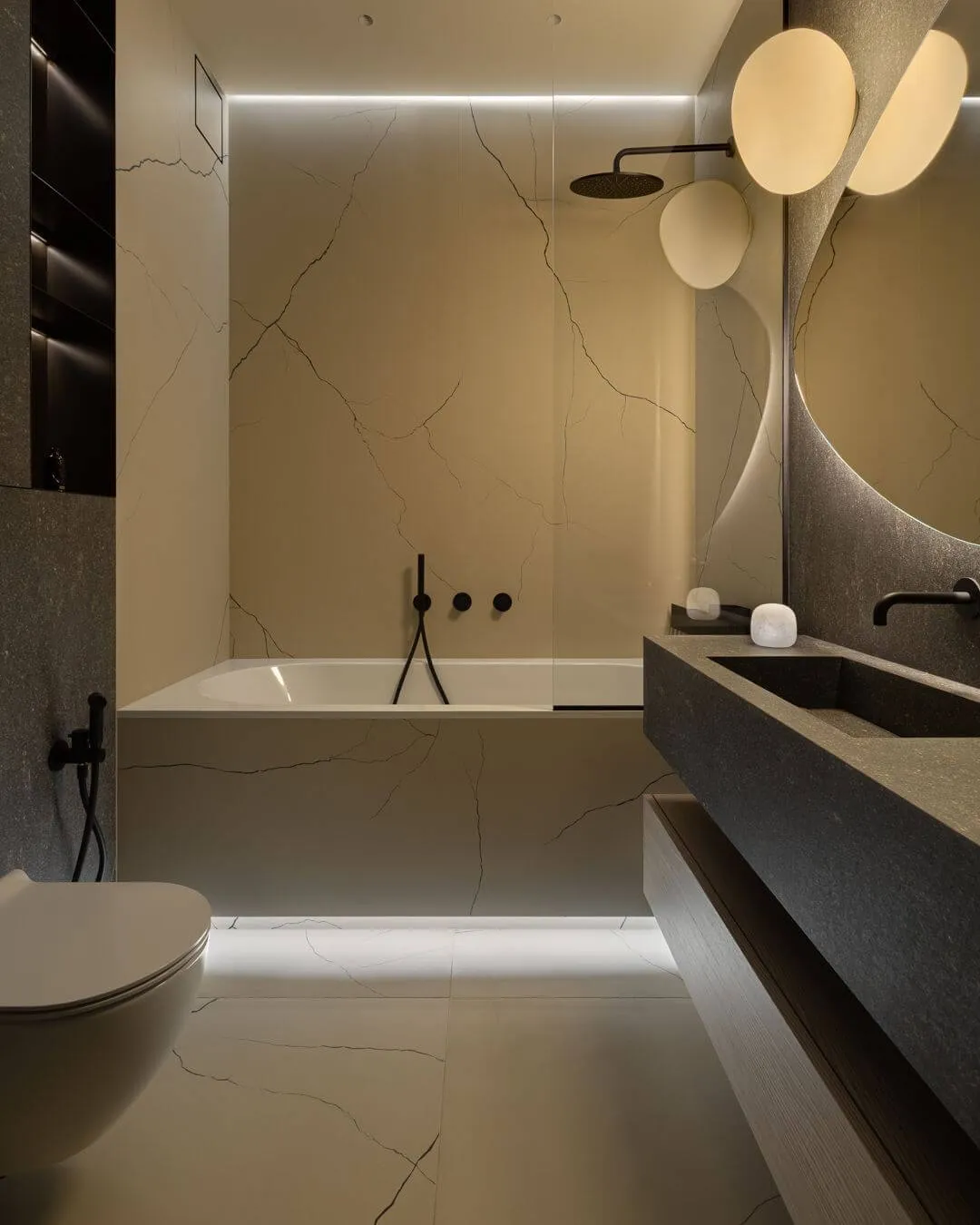 Інтер'єр гостьової ванни з двома видами керамограніту - бежевим із прожилками та темним, що нагадує базальт, білою ванною та чорною сантехнікою
