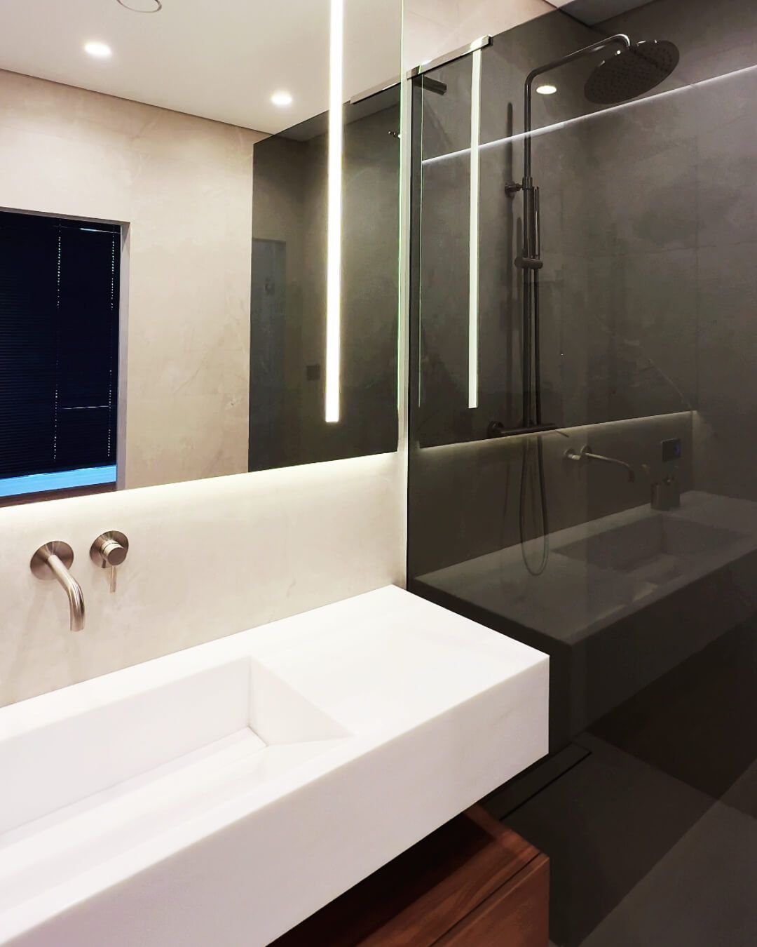 Санвузол із білим литим умивальником, вбудованим в стіну золотистим змішувачем, бежевою плиткою