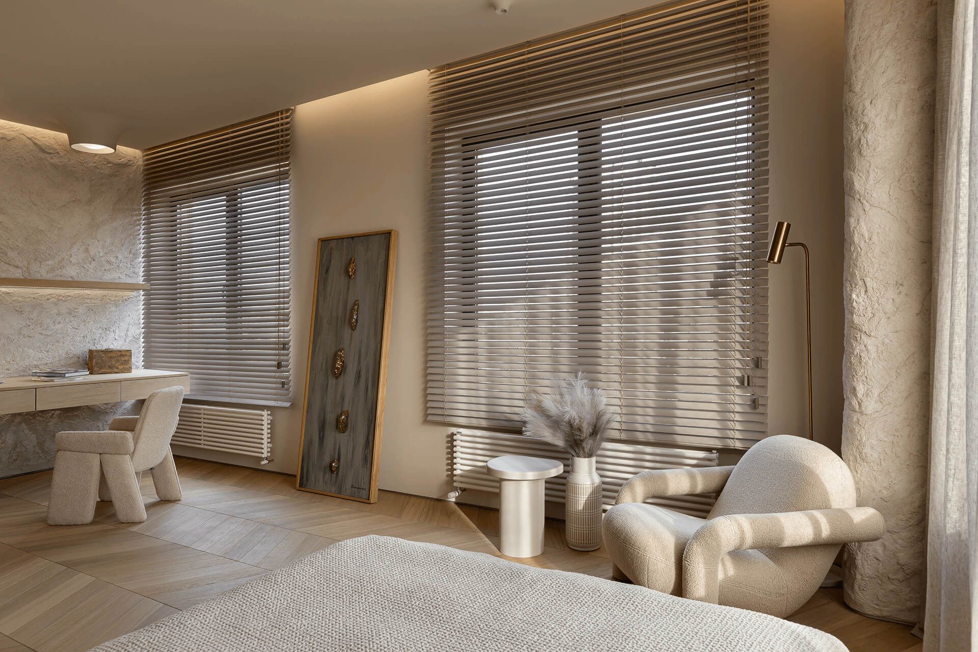 Спальня в бежевих тонах із кріслом, жалюзі на великих вікнах і торшером на високій ніжці