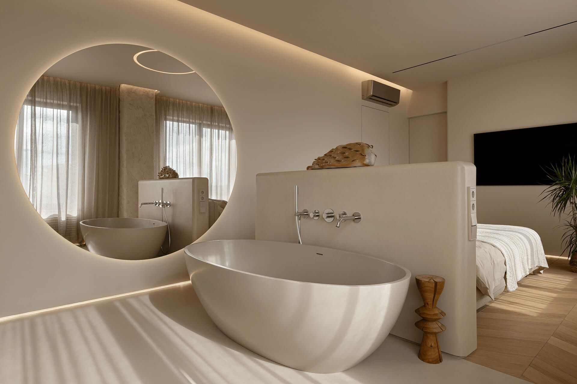 Спальня в бежевих тонах, з ванною за узголів'ям ліжка і круглим дзеркалом до стелі