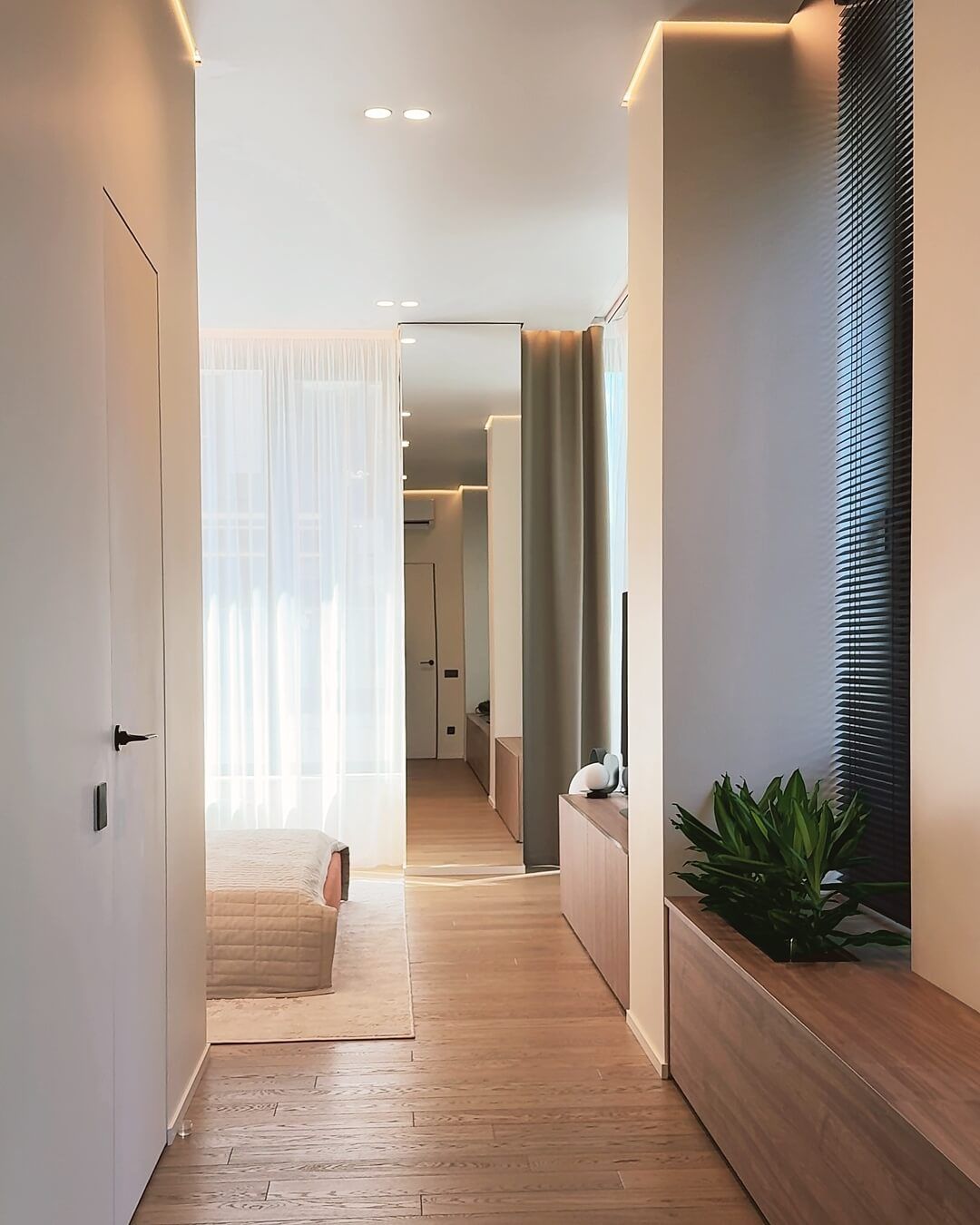 Коридор у спальні з дверима прихованого монтажу в санвузол та гардеробну, паркетом, та рослинами на підвіконні