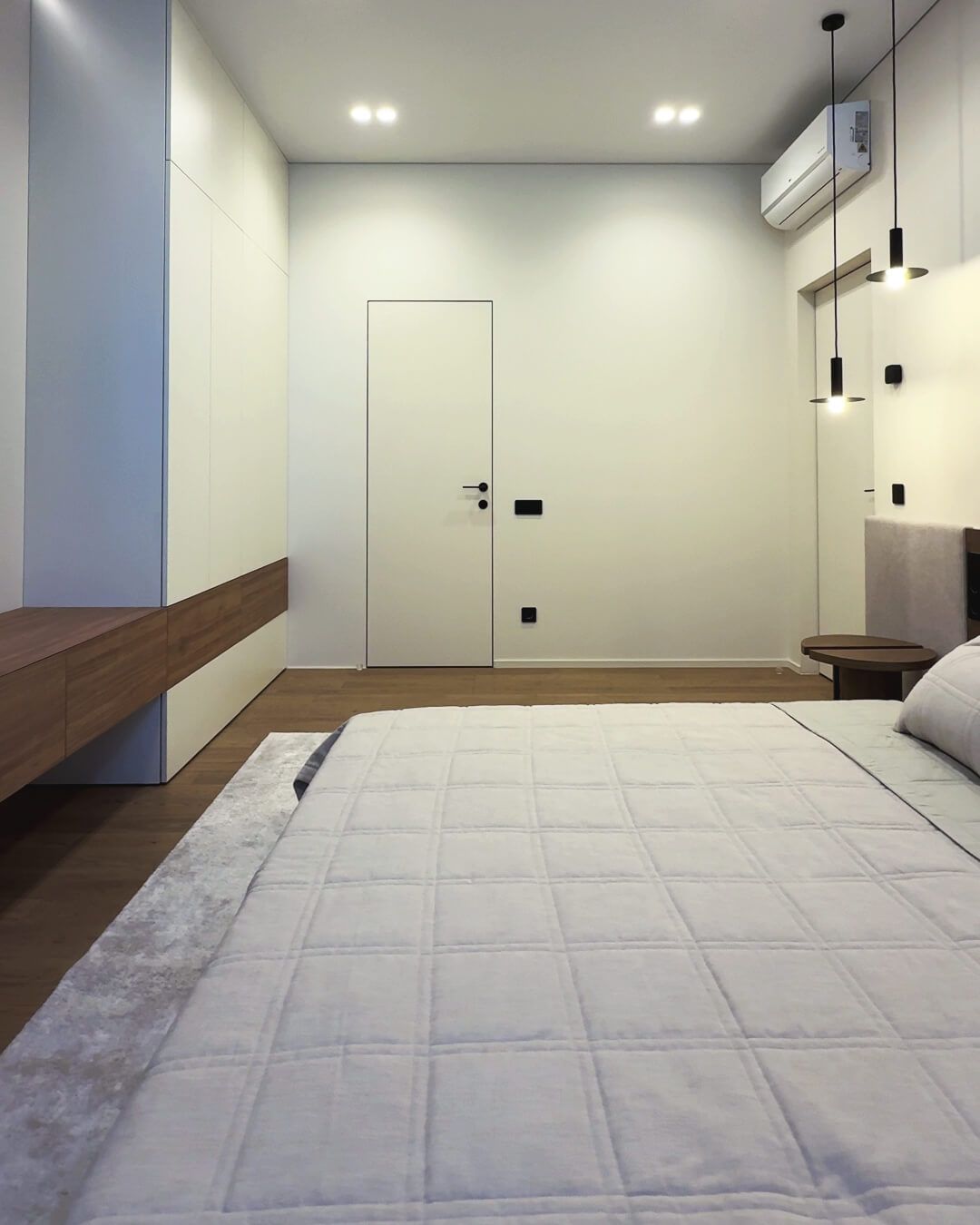 Гостьова спальня кремового кольору зі шафою до стелі, дверима прихованого монтажу, паркетом та окремим санвузлом