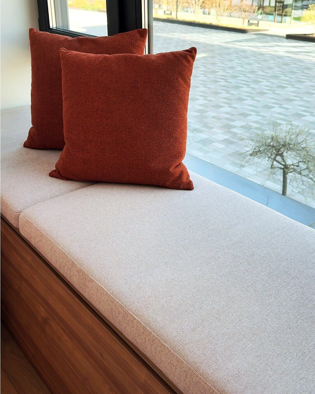 М'яке підвіконня у спальній з бежевими і теракотовими декоративними подушками