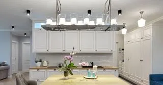 Світла кухня-вітальня в стилі сучасної класики, багатошаровим освітленням з підвісною скляною люстрою над островом