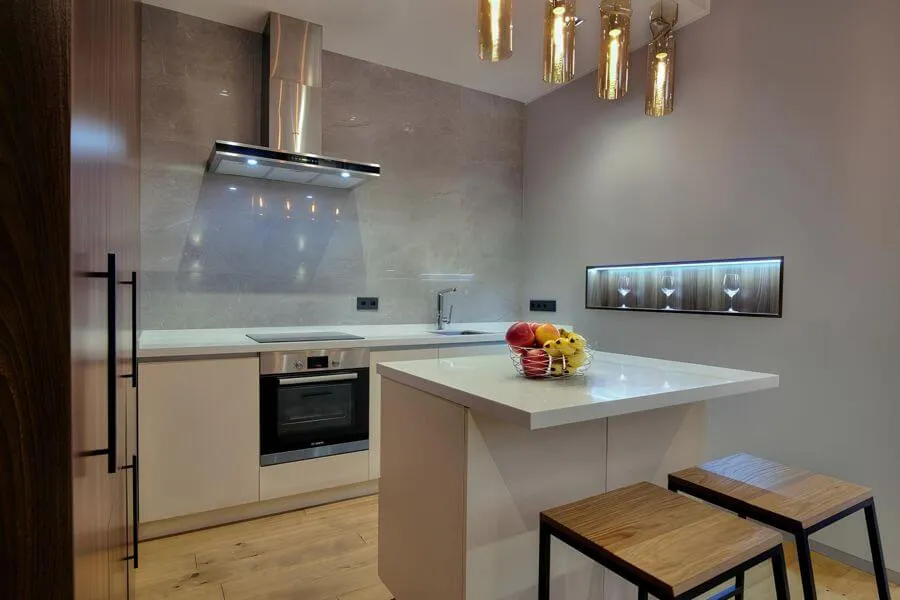 Мінімалістична кухня з білим островом, керамогранітною робочою стінкою і сталевою витяжкою