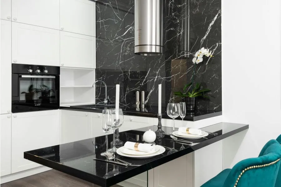 Контрастний інтер'єр кухні: білі фасади та стіна з керамограніту під чорний мармур
