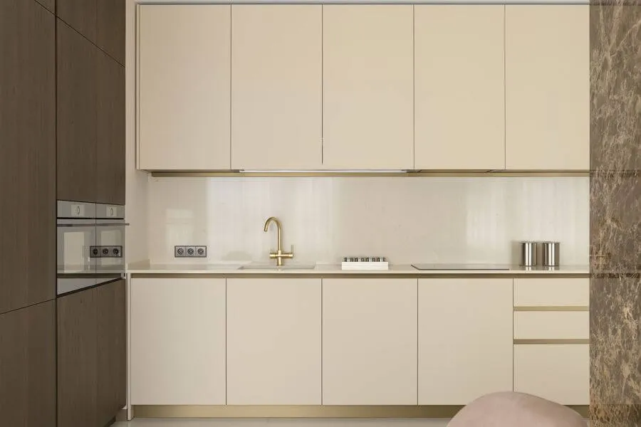 Кухня з темно-горіховими і кремовими фасадами, золотим змішувачем і фартухом зі штучного каменю
