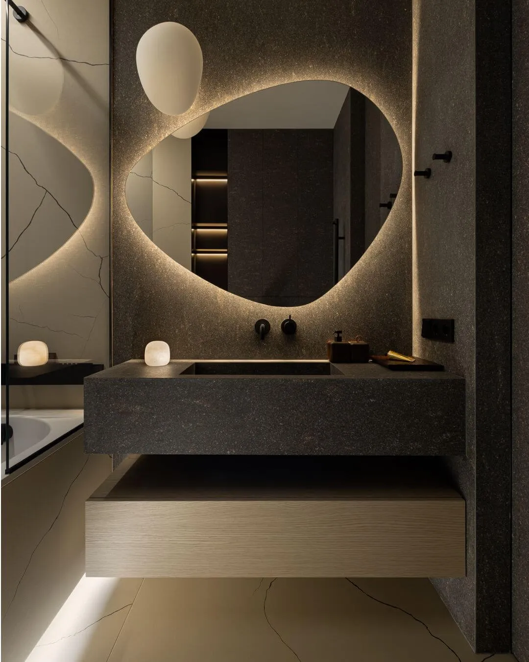 Гостьова ванна з темним керамогранітом під базальт, раковиной на підвісній тумбі, чорним змішувачем прихованого монтажу та дзеркалом неправильної форми