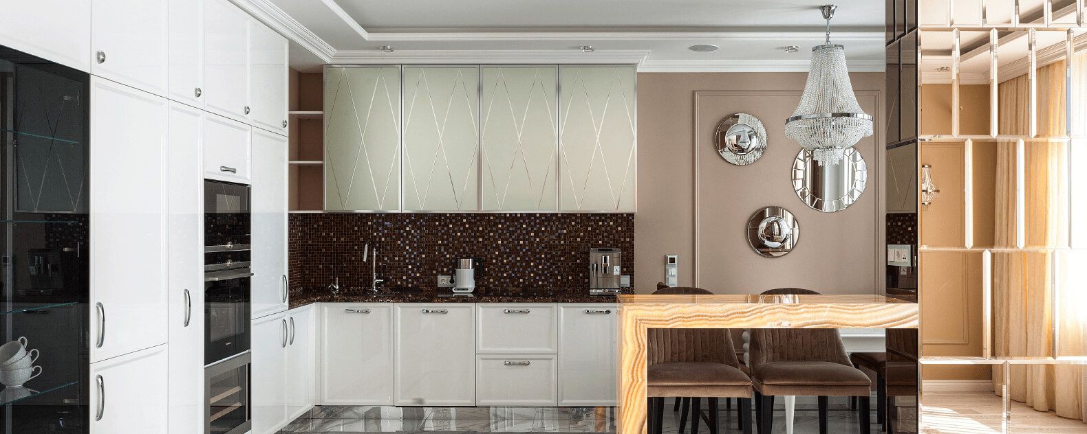 Інтер’єр кухні-вітальні з фасадами кремового кольору, мозаїкою на робочій зоні і люстрою в красичному стилі