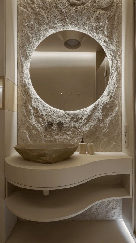 Санвузол, рель'єфна раковина з каменю на підвісній тумбі хвилястої форми, дзеркало з підсвіткою, декоративна штукатурка на стінах