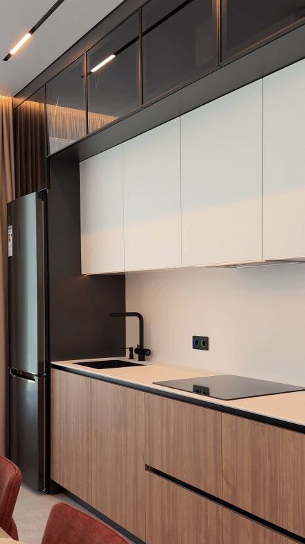 Кухня, нижні фасади - під світле дерево; верхні шафи - білі; антресолі, сантехніка і побутова техніка - чорні