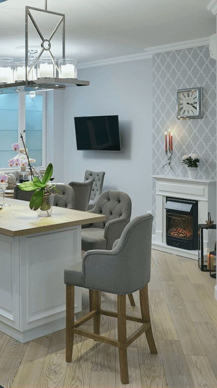 Інтер'єр кухня-вітальні, стіл-острівець і високі м'які крісла поруч, штучний камін, стильна люстра