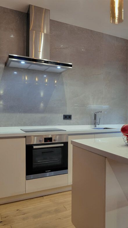 Кухня, без верхніх шаф, нижні фасади та столешня білі, на стіні плитка, витяжка з нержавійки,