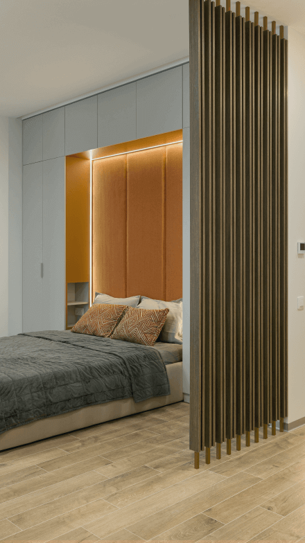 Ліжко, високе узголів'я з м'яким оздобленням помаранчевого кольору, вбудовані шафи під стелю, декоративна фальш-стіна