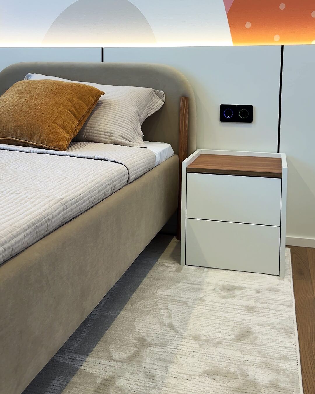 Ліжко із текстильним узголів'ям та дерев'яними елементами, мінімалістичною приліжковою тумбою та розетками на стіновий панелі
