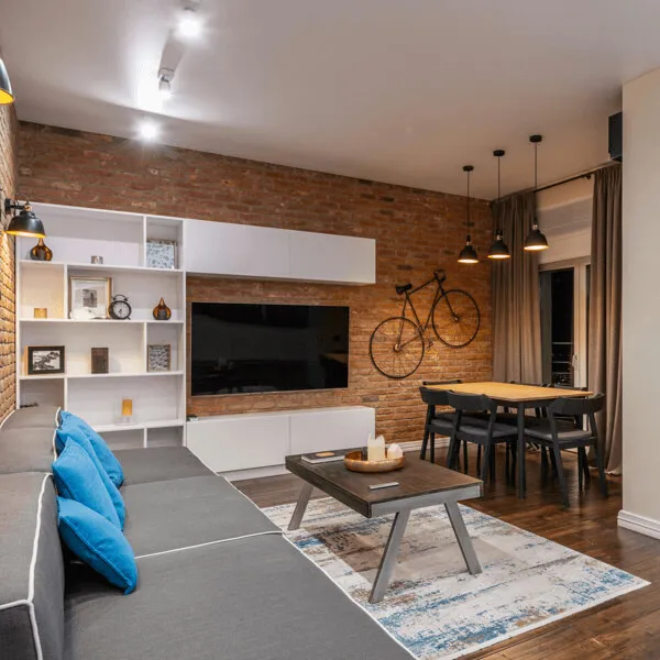 Інтер'єр кухні-вітальні в стилі лофт, з цегляною стелею, дерев'яним столом на металевих ніжках, мінімалістичні книжкові полиці