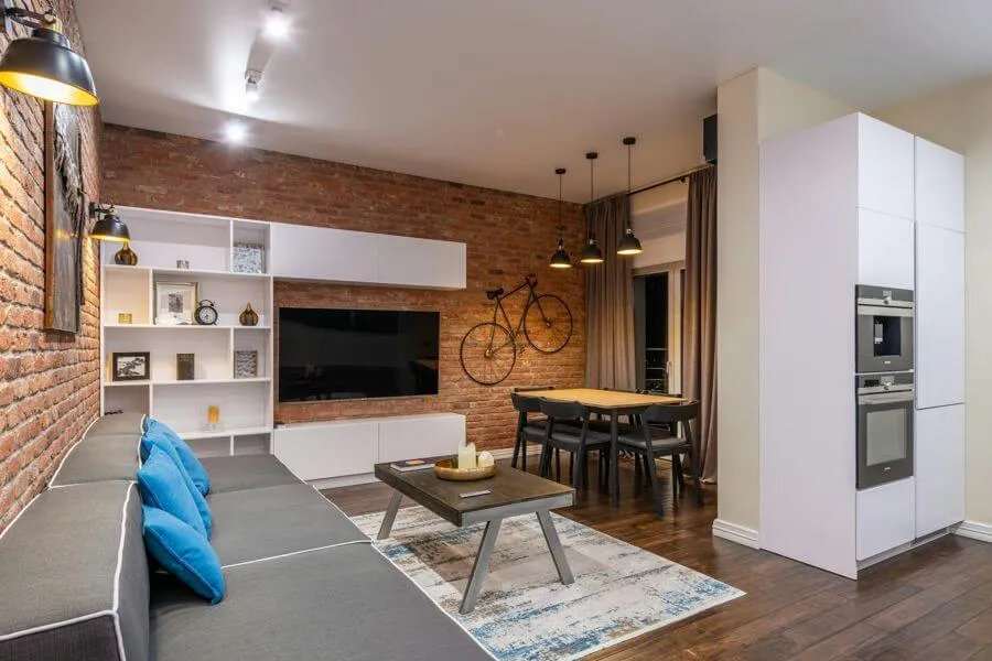 Інтер'єр кухні-вітальні в стилі лофт, з цегляною стелею, дерев'яним столом на металевих ніжках, мінімалістичні книжкові полиці