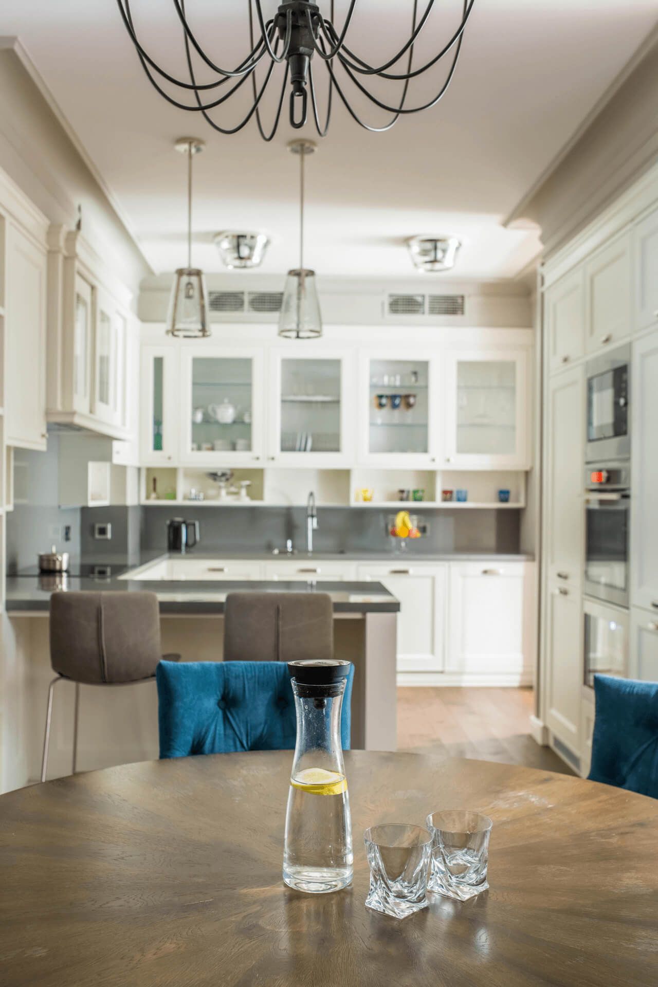 Кухня з білими фасадами, скляними верхніми шафками та вбудованою технікою