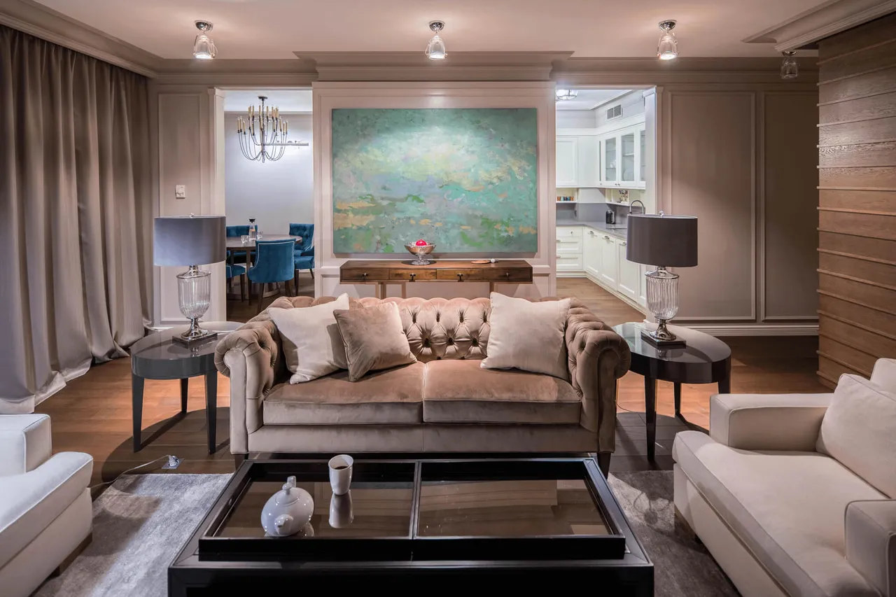 Вітальня з м’якою зоною, круглими столиками і торшерами, акцентною картиною та консольним столиком