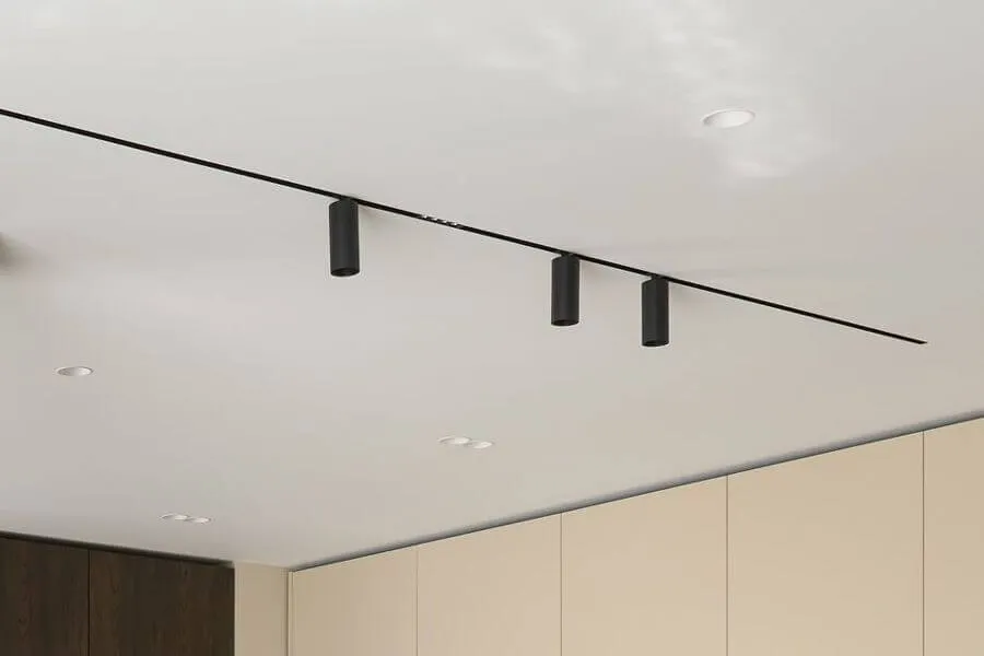 Чорна магнітна трекова система, вбудована в білу гіпсокартонну стелю, з трьома циліндричними спотами