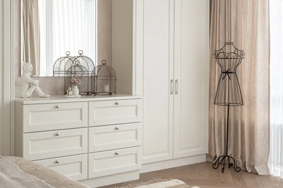 Дизайн інтер'єру у сучасному класичному стилі: білий комод, шафа та мінімалістичний декор (кований манекен та клітки для птахів)