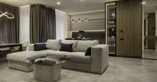 Інтер'єр кухні-вітальні в темних тонах з фасадом зі шпону, світильниками кубічної форми над островом, диваном і обідньої зоною біля вікна