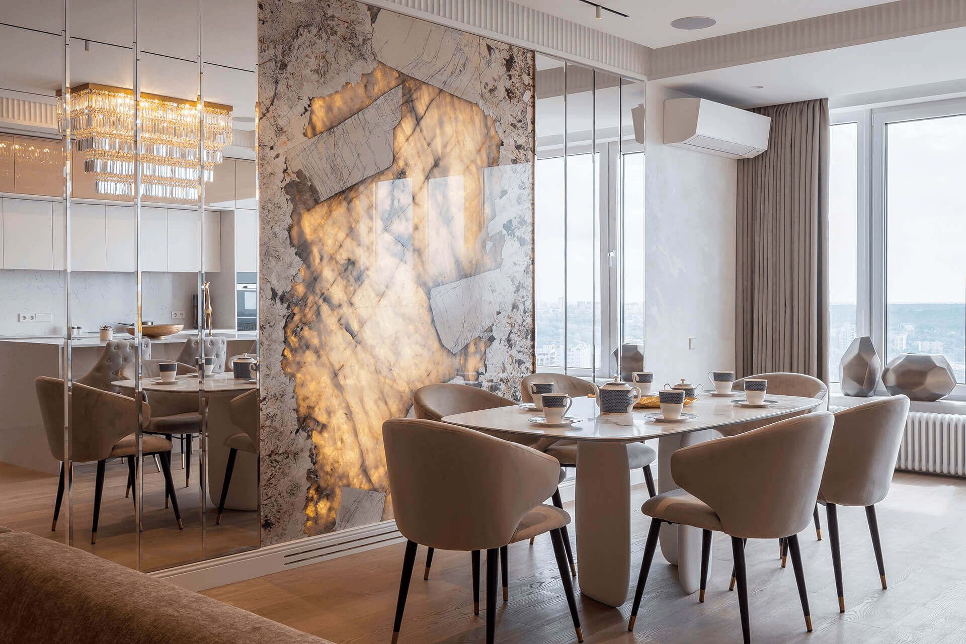 Обідня зона в кухні-вітальні з кварцитом Патагонія і фацетованими дзеркалами, білим столом і м'якими кріслами і паркетом