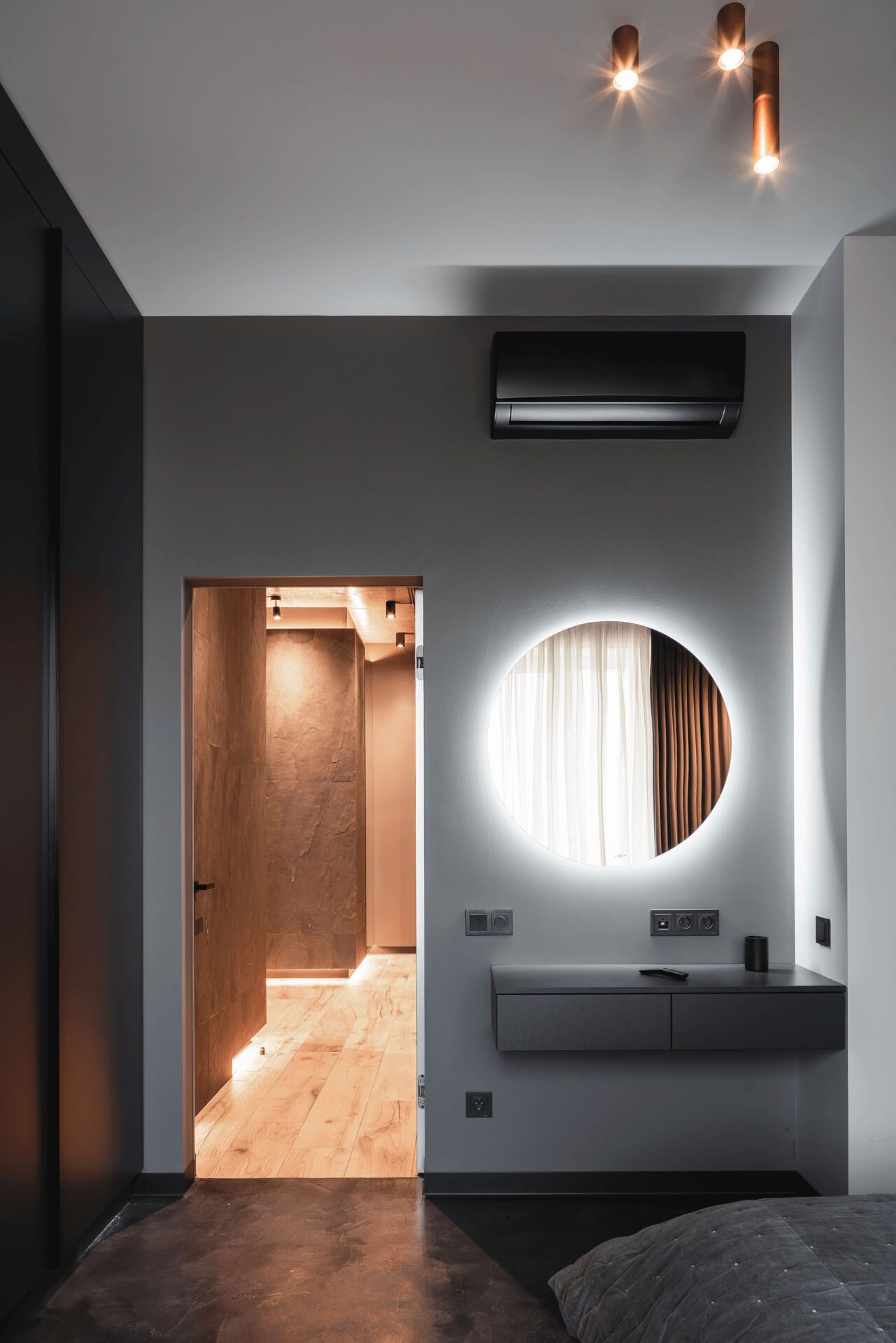 Лаконічний дизайн спальні з підвісним робочим столиком з шухлядами і круглим дзеркалом з підсвіткою над ним