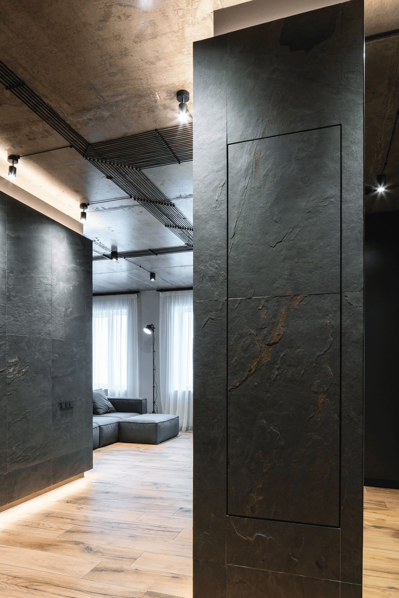 Коридор квартири в лофт стилі з бетонними стелями, стінами оздобленими кам'яним шпоном і дерев'яною підлогою