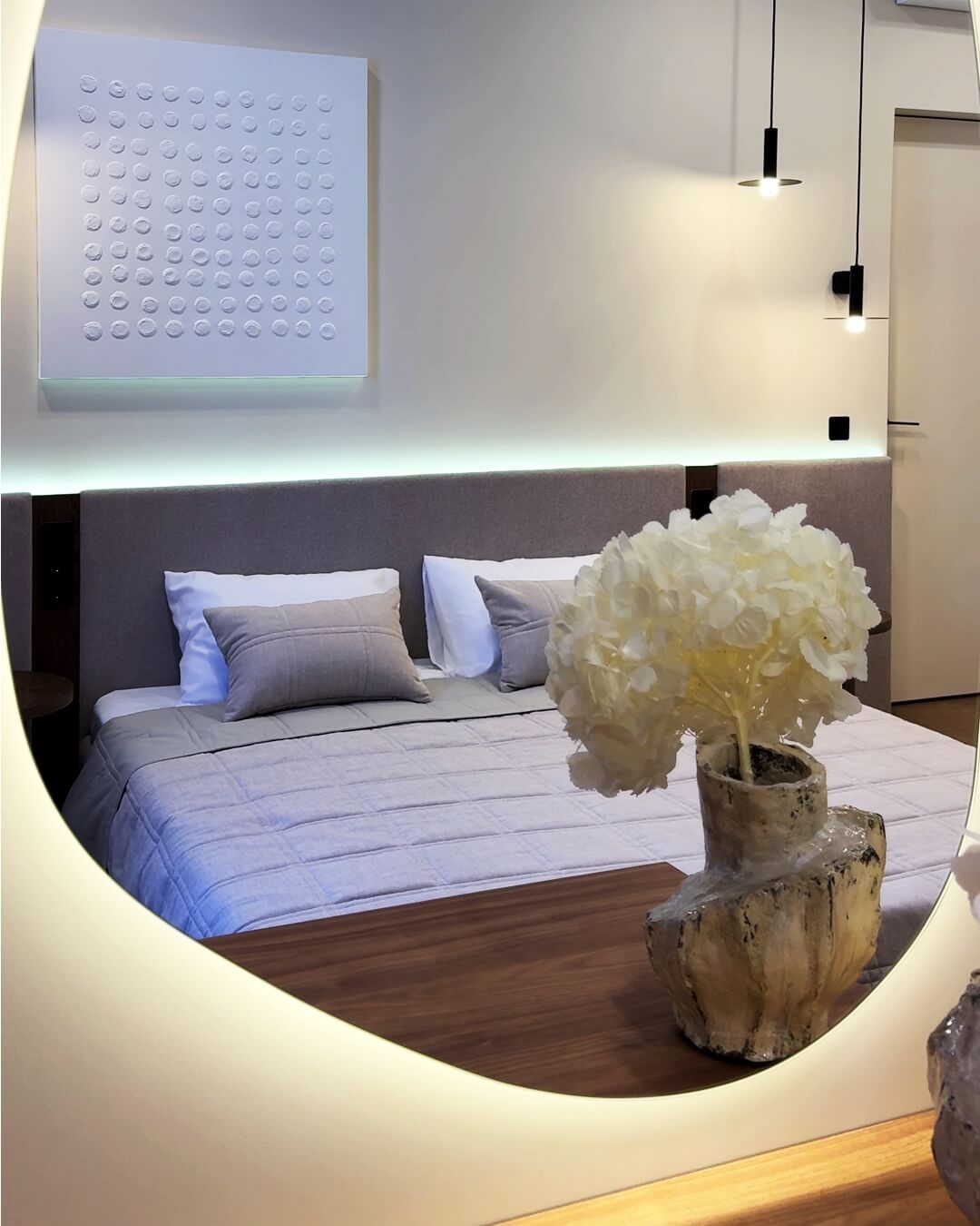 Інтер'єр гостьової спальні з дзеркалом для макіяжу, білим декоративним квадратом над ліжком і підвісними чорними світильниками