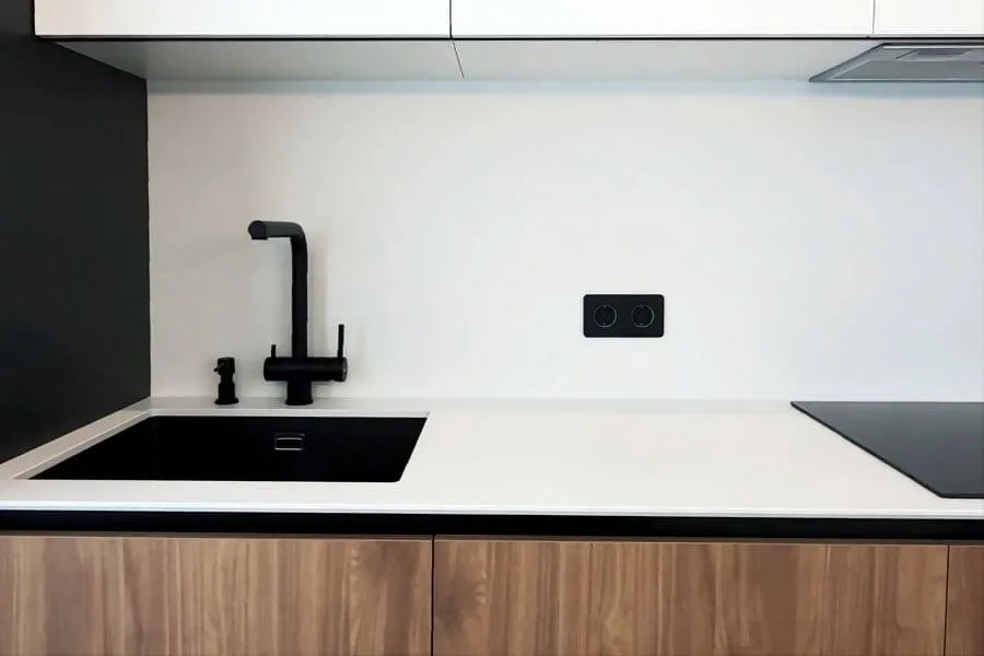 Кухонний фартух і стільниця зі штучного каменю білого кольору і чорна сантехніка