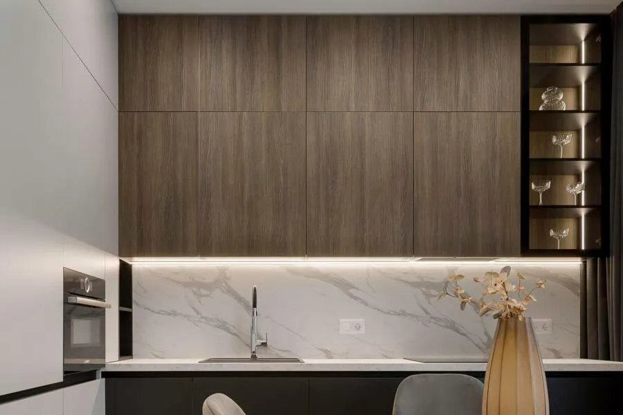 Кухня з фасадами зі шпону темної деревини, білою стільницею і фартухом, вбудованою духовою шафою